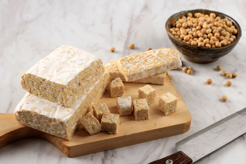 Raw Tempeh or Tempe. Tempeh Slices on Wooden Background, Cut by